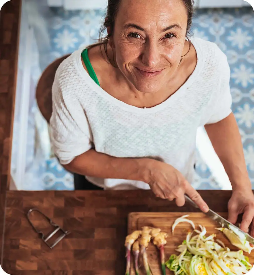 Mujer cortando comida en una tabla para cortar